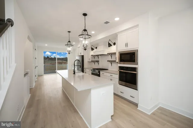 a large kitchen with stainless steel appliances kitchen island a large counter top a stove and a chandelier