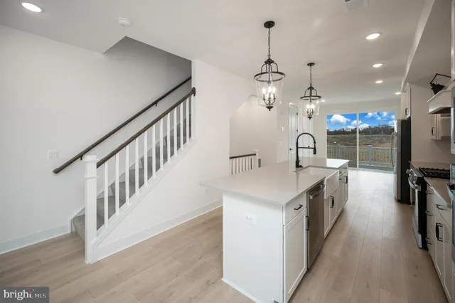 a kitchen with stainless steel appliances granite countertop a sink a stove a refrigerator and island with wooden floor