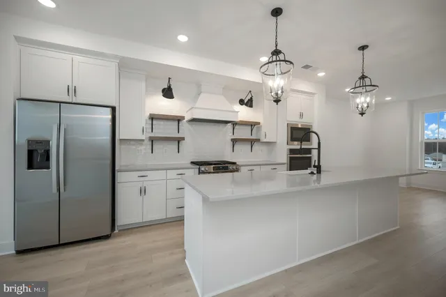 a kitchen with stainless steel appliances a stove and white cabinets