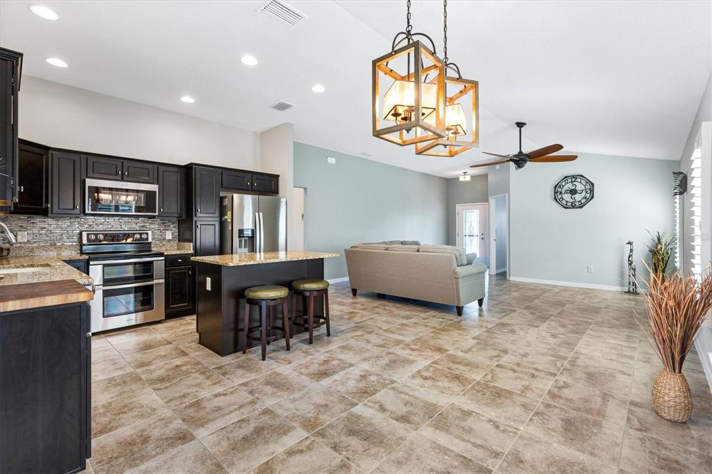 7351 Southeast 169th Cote Loop The Villages, FL 32162 - Photo 12 of 32 a living room with furniture a flat screen tv and kitchen area