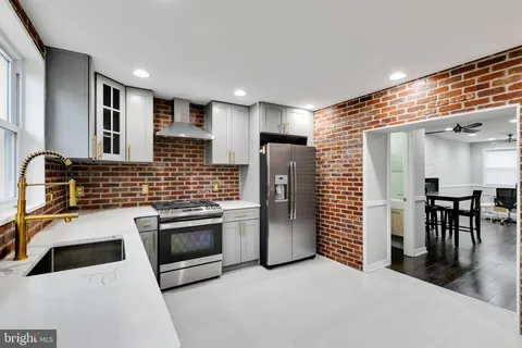 a kitchen with stainless steel appliances a stove a sink a refrigerator white cabinets and wooden floor