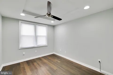an empty room with wooden floor fan and windows