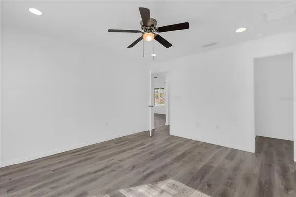 a view of empty room with wooden floor and ceiling fan