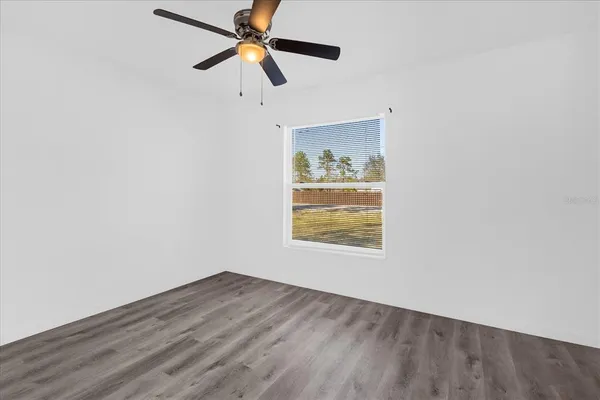 an empty room with wooden floor and ceiling fan