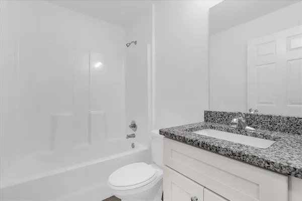 a bathroom with a granite countertop sink a toilet and bathtub