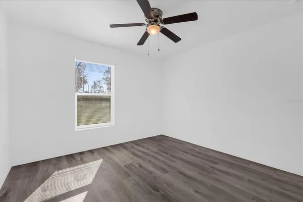 an empty room with a window and a ceiling fan