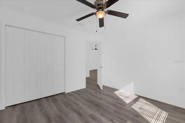 an empty room with wooden floor closet and windows