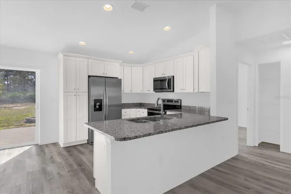 a kitchen with stainless steel appliances granite countertop a refrigerator a stove a sink and a microwave