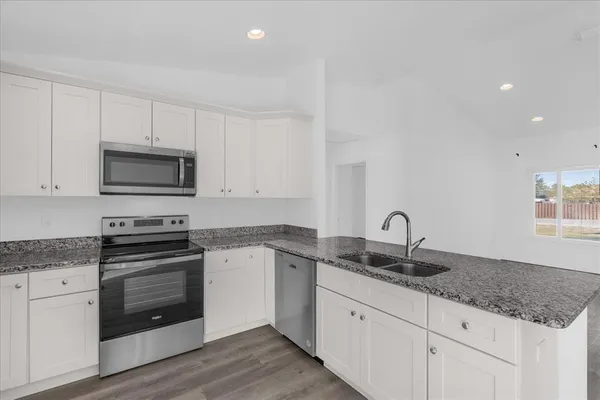 a kitchen with granite countertop a sink and a stove top oven