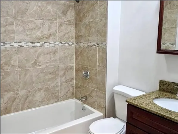 a bathroom with a granite countertop bathtub toilet and sink