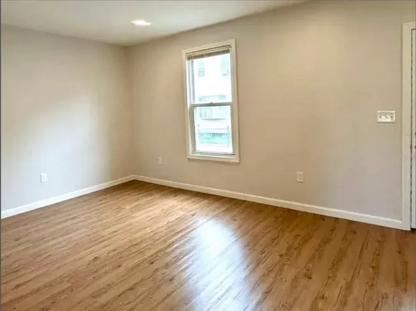 an empty room with wooden floor and window