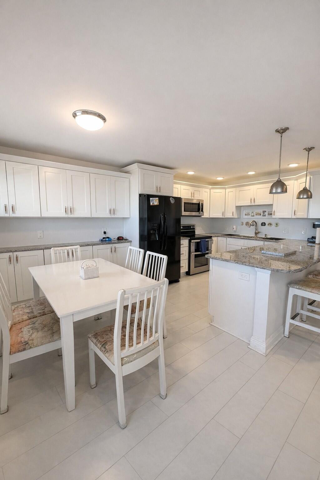 4057 Wolverton C Boca Raton, FL 33434 - Photo 3 of 8 a kitchen with a table chairs sink and cabinets