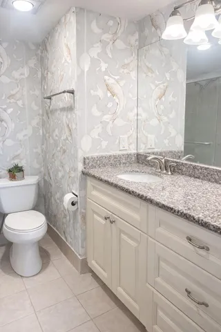 a bathroom with a granite countertop sink a toilet and a shower