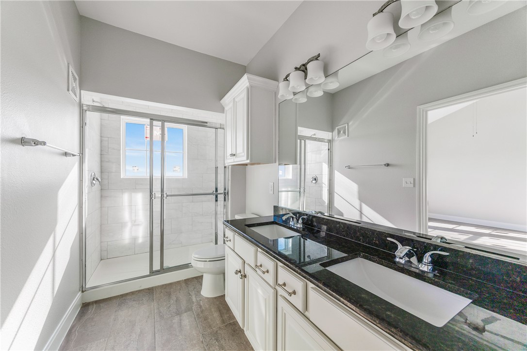 14814 Whitecap Boulevard Corpus Christi, TX 78418 - Photo 29 of 40 a large bathroom with a granite countertop sink a large mirror a toilet and a shower