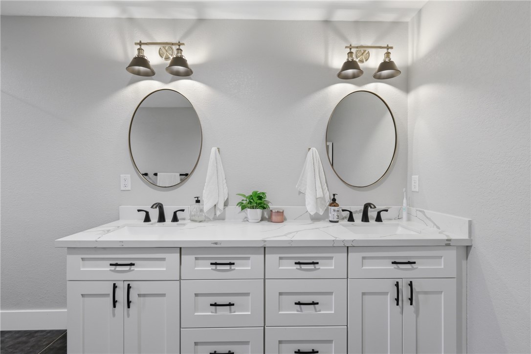 515 Crescent Drive Bryan, TX 77801 - Photo 21 of 43 Dual vanity with white cabinetry and black hardware, featuring a white countertop, two oval mirrors, and individual sconce lighting