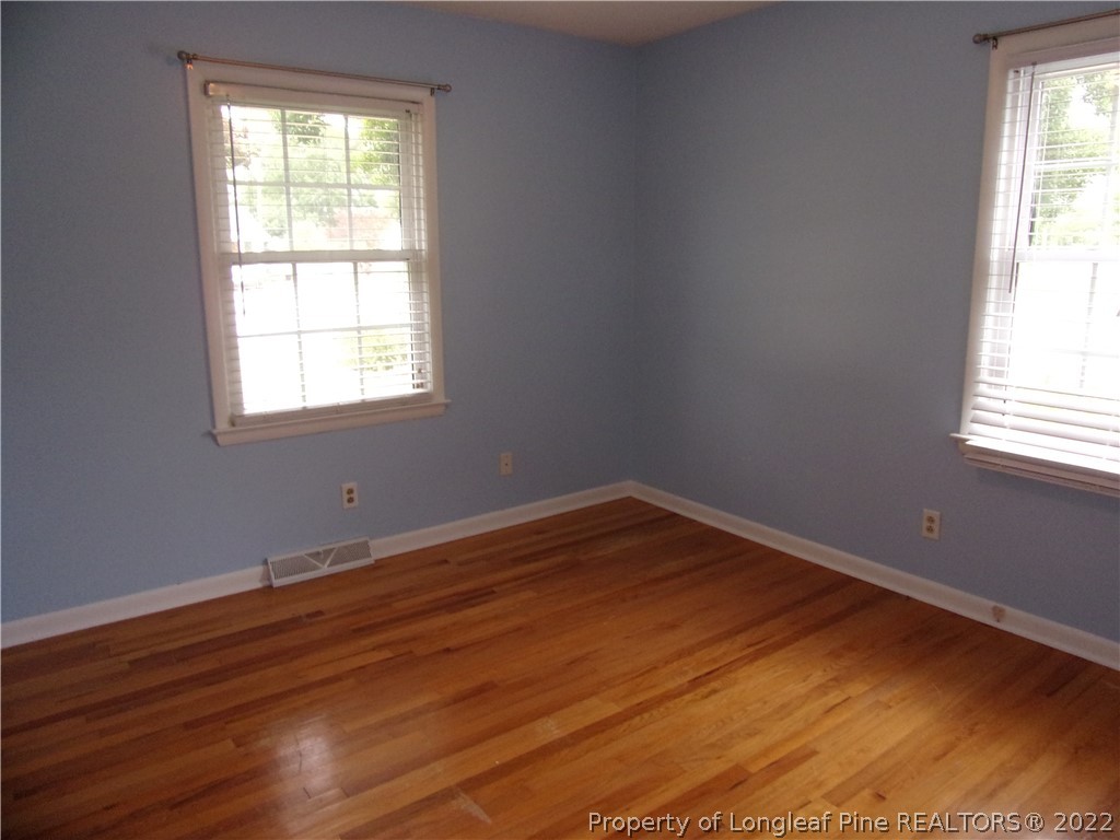 1503 Fairview Street Dunn, NC 28334 - Photo 9 of 10 an empty room with wooden floor and windows
