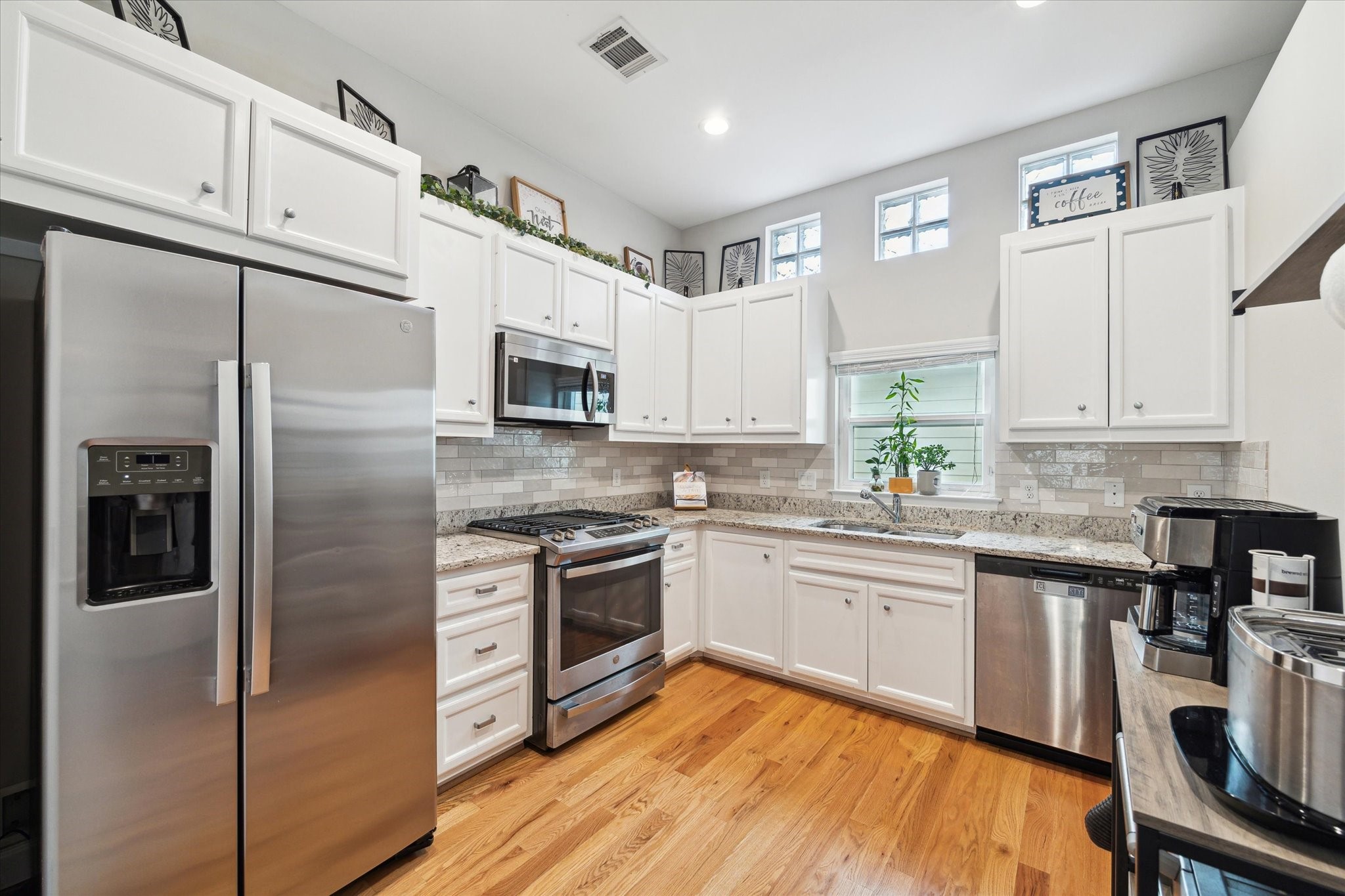 a kitchen with granite countertop stainless steel appliances a sink cabinets and a refrigerator