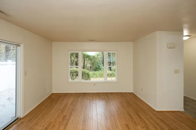 an empty room with wooden floor and windows
