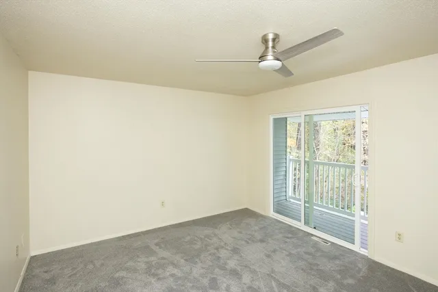 an empty room with ceiling fan and window