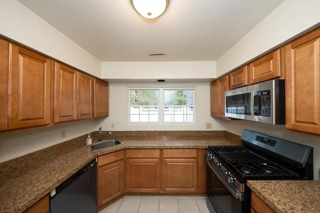 a kitchen with granite countertop a stove a sink and a microwave