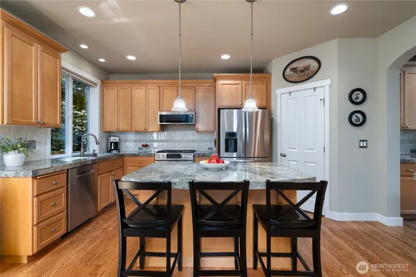 a kitchen with stainless steel appliances granite countertop a kitchen island hardwood floor sink and stove