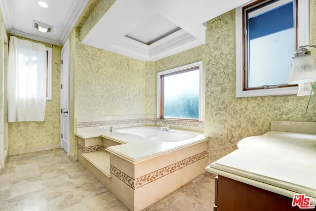 a spacious bathroom with a tub a sink and a mirror