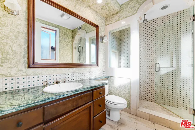 a bathroom with a granite countertop toilet a sink a mirror and shower