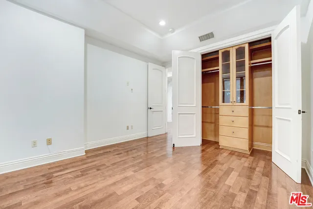 an empty room with wooden floor and cabinet