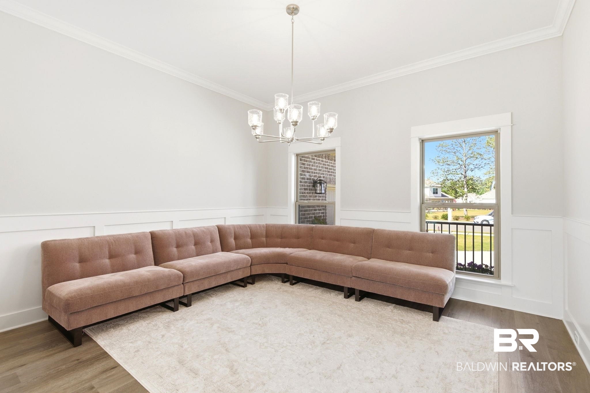 12132 Exbury Way Daphne, AL 36527 - Photo 8 of 47 Living area featuring a decorative wall, wainscoting, wood finished floors, ornamental molding, and a chandelier