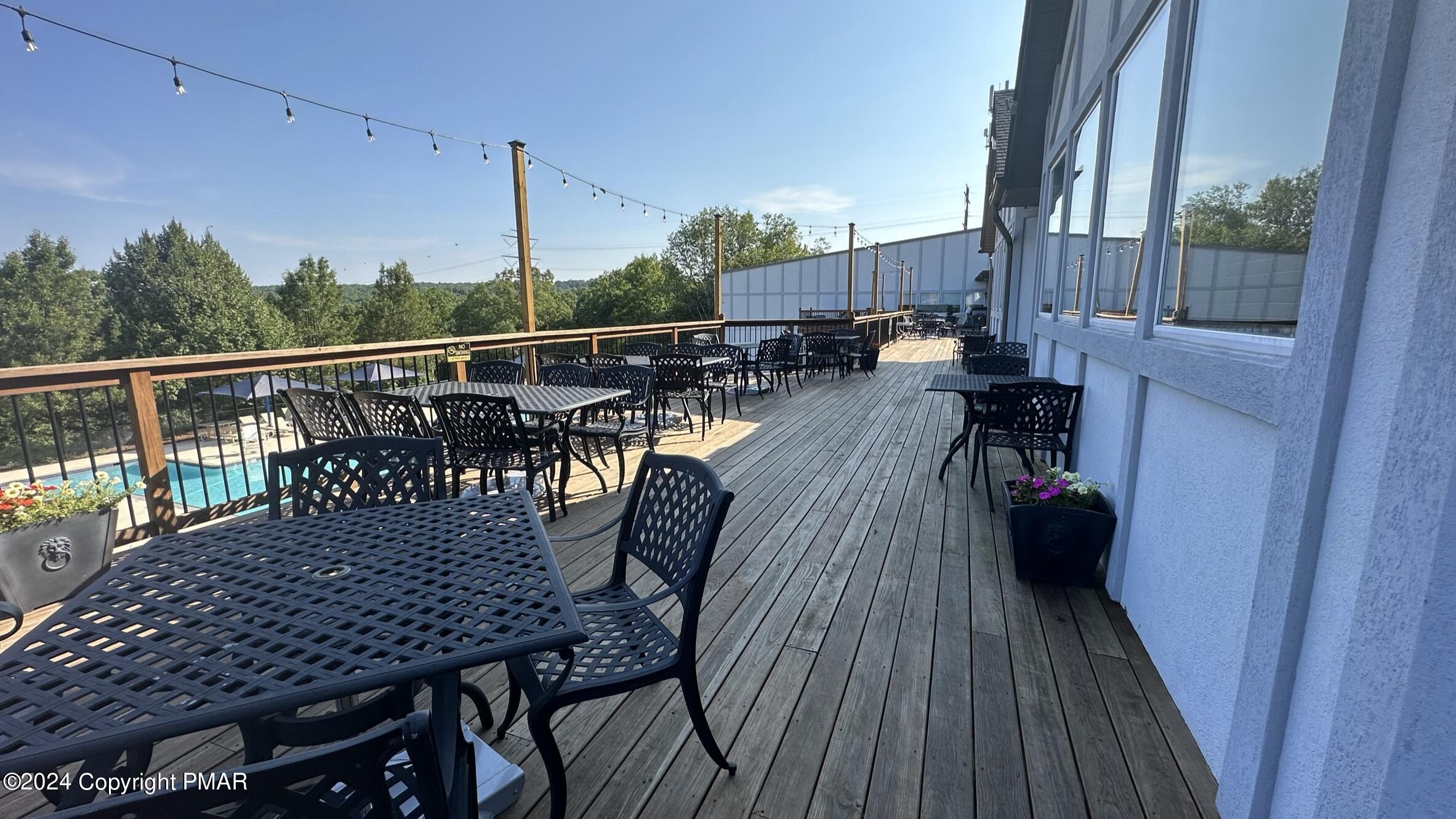 Lot 139 Berkshire Court Bushkill, PA 18324 - Photo 36 of 52 a view of a roof deck with table and chairs with wooden floor and fence