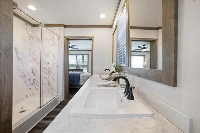 a en suite bathroom with a granite countertop tub sink and glass door