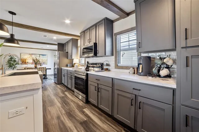 a kitchen with a sink dishwasher stove and white cabinets with wooden floor