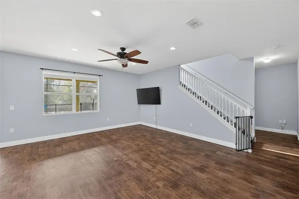 a view of an empty room with a window and wooden floor