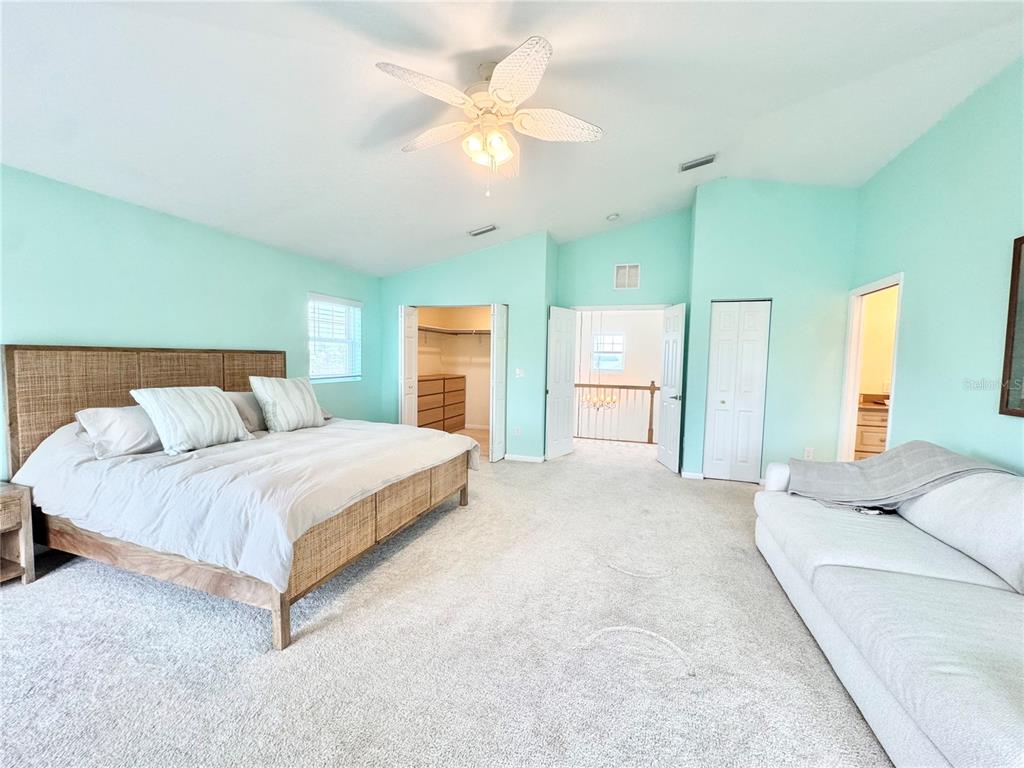 16204 3rd Street East Redington Beach, FL 33708 - Photo 28 of 58 a spacious bedroom with a large bed a chandelier with vanity and mirror