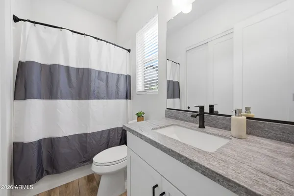 a bathroom with a granite countertop bathtub sink vanity mirror and toilet