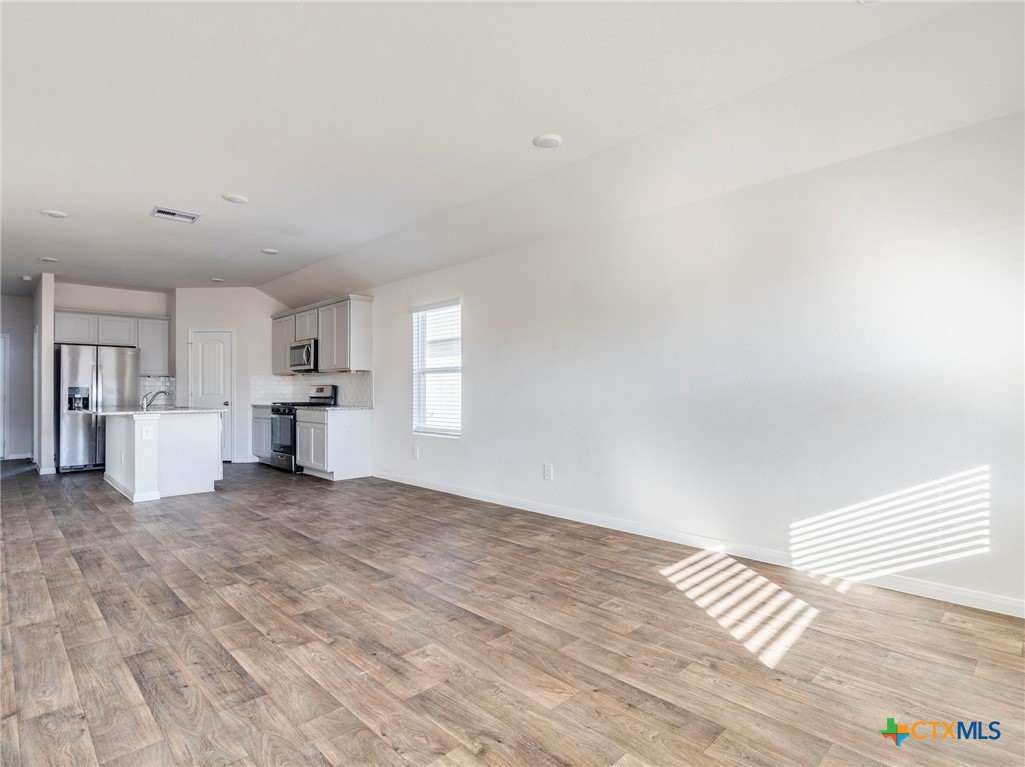 316 Addison Place Lockhart, TX 78644 - Photo 11 of 28 a view of empty room with wooden floor and kitchen