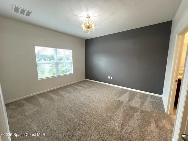 an empty room with windows and chandelier fan
