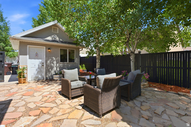 5196 Rodeo Circle Oakley, UT 84055 - Photo 49 of 57 Flagstone patio featuring mature trees, a privacy fence, an exterior building with a single window, and a wall-mounted exterior light fixture