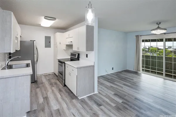 a kitchen with stainless steel appliances a stove top oven a refrigerator a sink and dishwasher with wooden floor