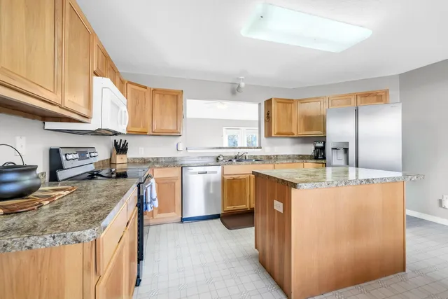 a kitchen with stainless steel appliances granite countertop a stove a sink and a refrigerator