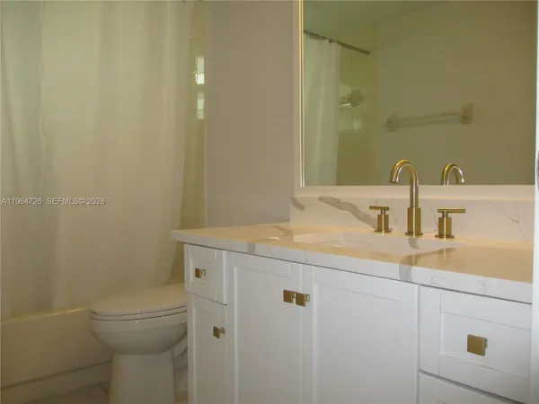 a bathroom with a granite countertop sink a toilet and a mirror