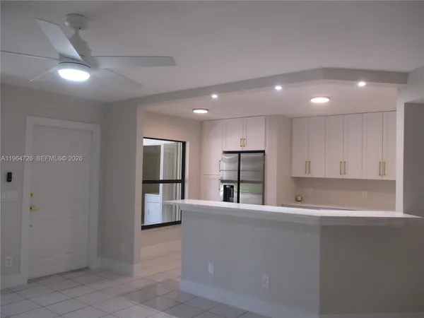 a living room with stainless steel appliances kitchen island granite countertop a refrigerator and a sink