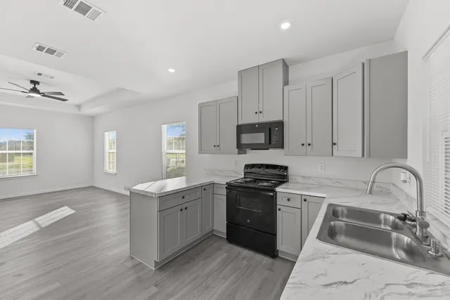 a kitchen with granite countertop a sink stove and cabinets
