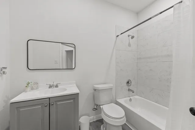 a bathroom with a toilet sink vanity tub and mirror
