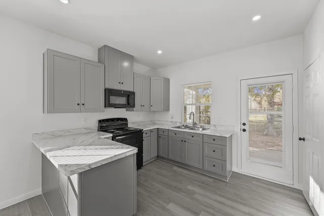 a kitchen with granite countertop stainless steel appliances a sink stove and refrigerator