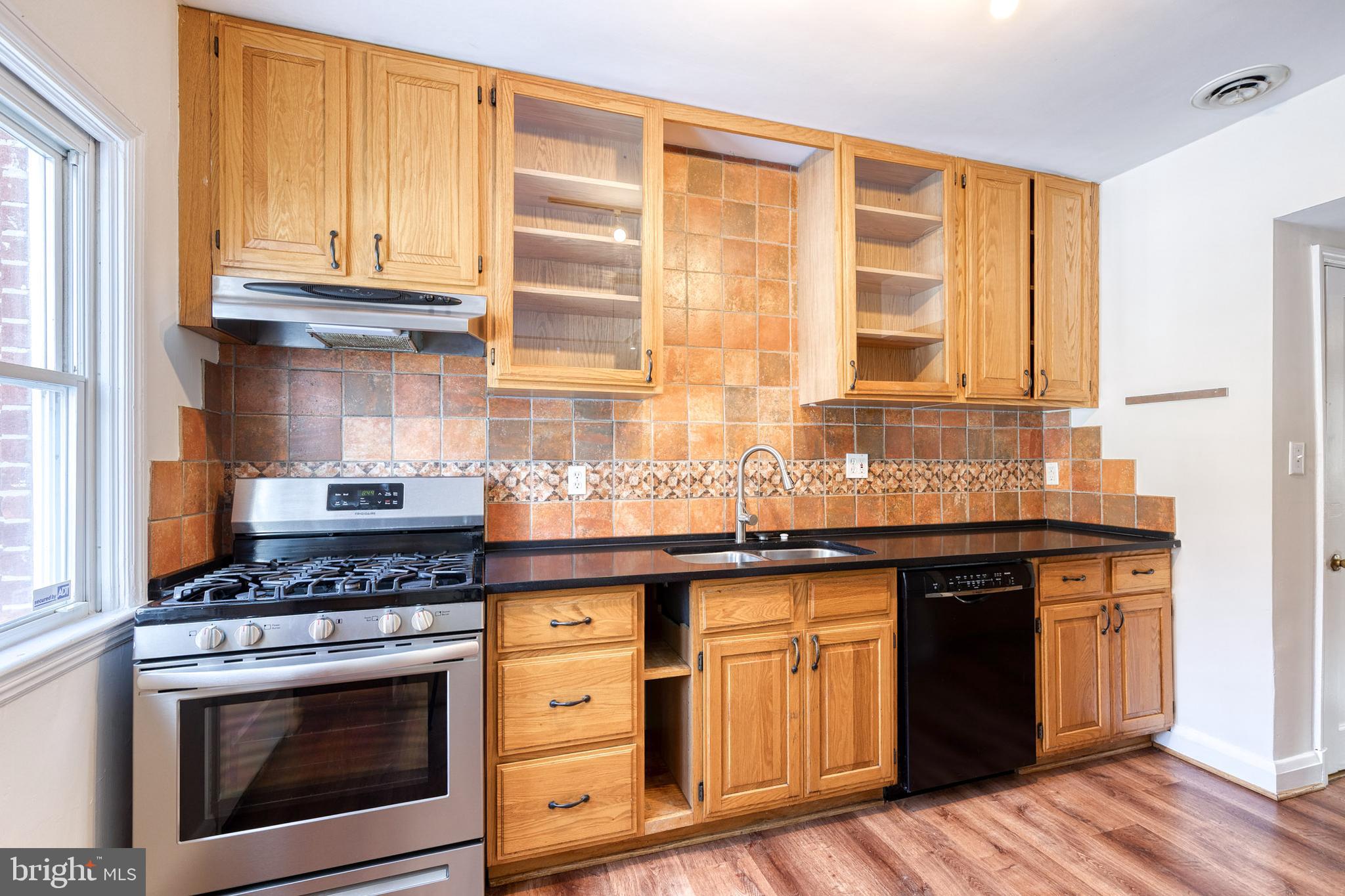 3918 Beech Avenue Baltimore, MD 21211 - Photo 11 of 24 a kitchen with granite countertop a stove a sink and wooden cabinets