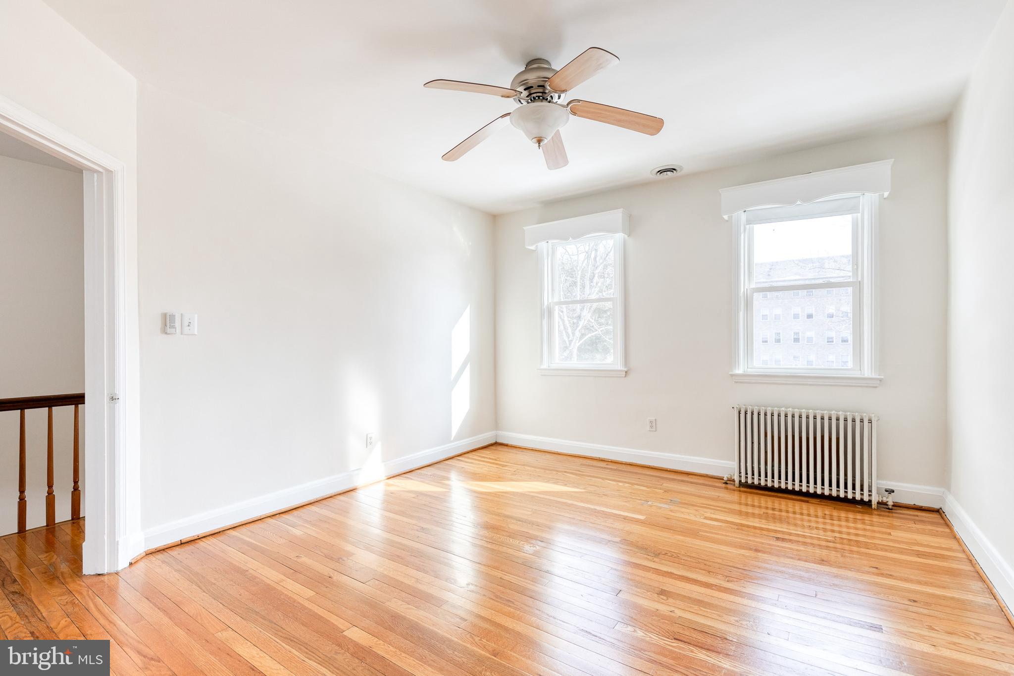 3918 Beech Avenue Baltimore, MD 21211 - Photo 16 of 24 an empty room with wooden floor chandelier fan and windows