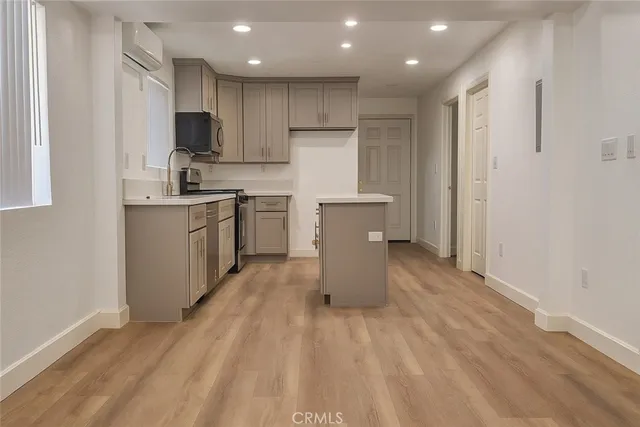 a large kitchen with kitchen island granite countertop a stove top oven a sink a counter space and cabinets