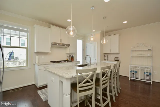 a kitchen with stainless steel appliances granite countertop a kitchen island a stove a table and a refrigerator