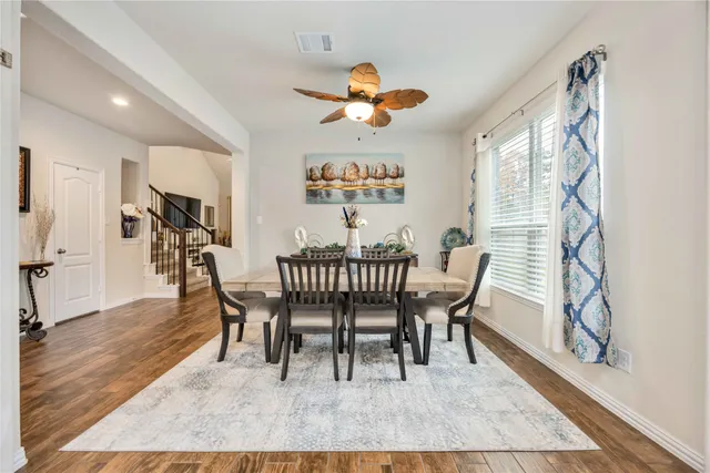 a dining room with wooden floor a chandelier a wooden table and chairs